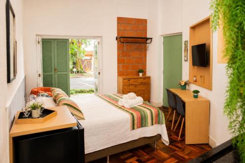 ein Schlafzimmer mit Bett, Schreibtisch und Fenster in der Unterkunft Loft Veneto in Maringá