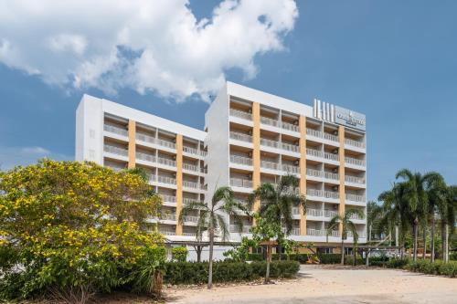 a large white building with palm trees in front of it at Manditel North Pattaya in North Pattaya