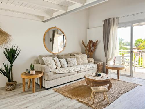 a living room with a couch and tables and a mirror at Duplex La Plage Orient Bay in Orient Bay