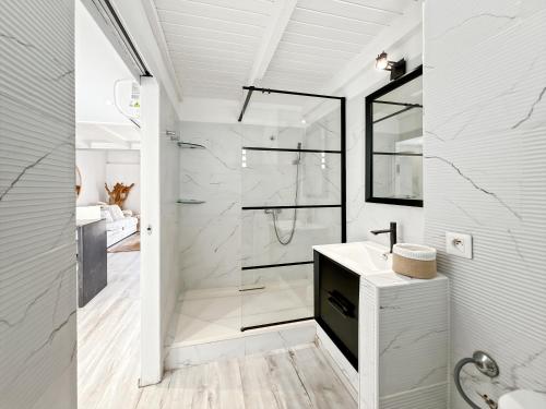 a white bathroom with a shower and a sink at Duplex La Plage Orient Bay in Orient Bay