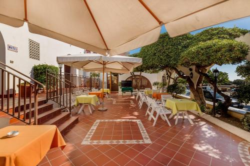 a patio with tables and chairs and umbrellas at Hotel El Balear in Alghero