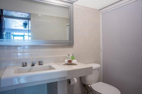 a bathroom with a sink and a toilet and a mirror at Toca Madera in Chapala