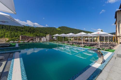 a pool at a resort with chairs and umbrellas at Gold Palace SPA Resort Bukovel in Bukovel
