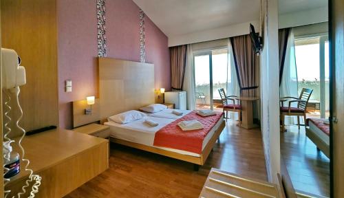 a hotel room with a bed and a table and chairs at Sandy Bay Hotel in Plomari
