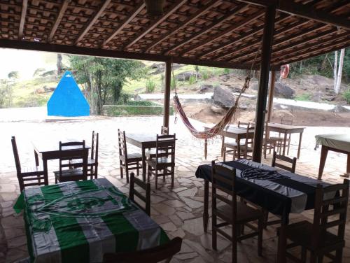 ein Restaurant mit Tischen, Stühlen und einer Hängematte in der Unterkunft Camping 4m in Aiuruoca