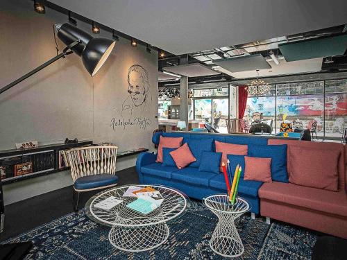 a living room with a blue couch and a table at ibis Styles Genève Carouge in Geneva