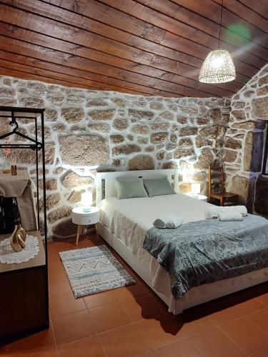 a bedroom with a bed in a stone wall at Casa D'Zelo - Gerês in Montalegre