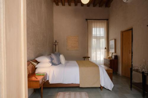 a bedroom with a white bed and a window at Hotel Hércules in Querétaro