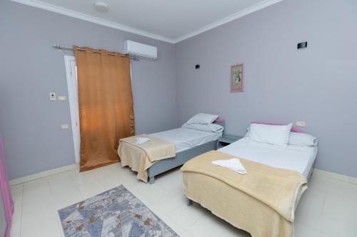 a room with two beds and a window at El Agamy Hotel Apartment in Luxor