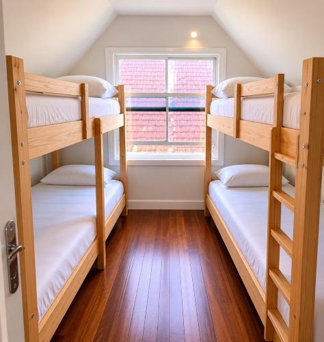 two bunk beds in a room with a window at ParaHouse in Joinville