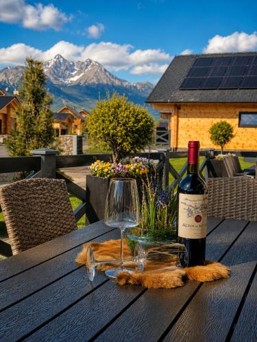 a bottle of wine and a glass on a wooden table at Vila Valentina Luxury Chalet in High Tatras in Veľká Lomnica