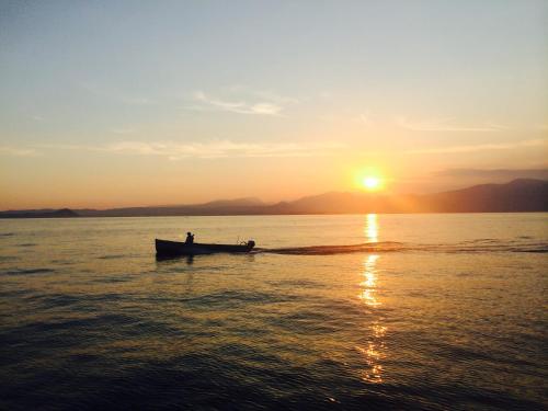 a man in a boat on the water at sunset at Castello Oldofredi in Monte Isola