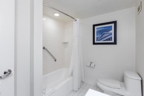 a white bathroom with a tub and a toilet at Metro Points Hotel Washington North in New Carrollton