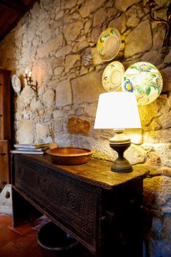 Eine Lampe auf einem Holztisch vor einer Steinwand in der Unterkunft Casa do General in Afife