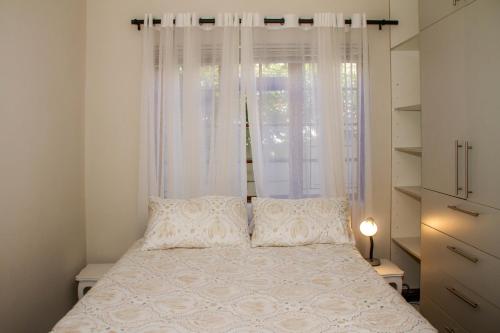 a bedroom with a white bed with a window at Cote Cottage in Somerset West