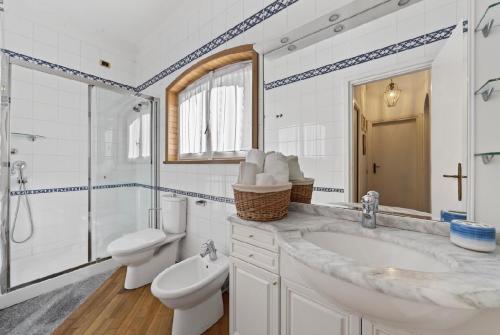 a white bathroom with a sink and a toilet at Casa Donata by Gottschalk in Lierna