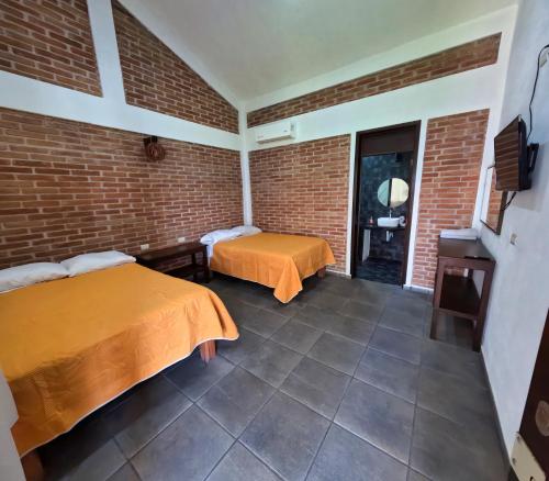a room with two beds and a brick wall at Villa Esmeralda del Mar in Monte Gordo