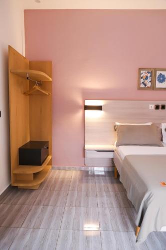 a bedroom with pink walls and a bed and a cabinet at Résidences AMAN in Morofé