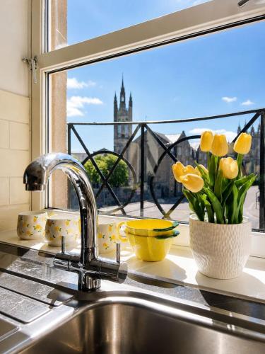 a kitchen sink with a window with yellow tulips at GALLOWGATE - CITY CENTRE - Free PRIVATE PARKING in Aberdeen