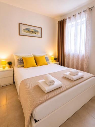 a bedroom with a large white bed with yellow pillows at Komiža Sea Breeze in Komiža