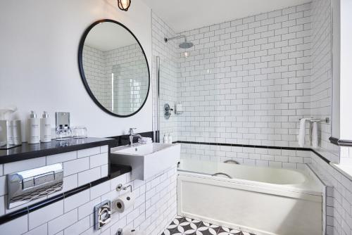 un bagno con vasca, lavandino e specchio di Titanic Hotel Belfast a Belfast