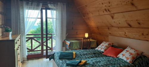 a bedroom with a bed and a large window at Góralska Ostoja - tradycyjny, drewniany dom na Kudłaczach, duży ogród, piękna panorama, sauna, jacuzzi in Pcim