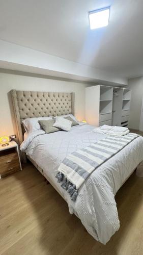 a bedroom with a large white bed with a large headboard at Luxury Towers Arequipa in Arequipa