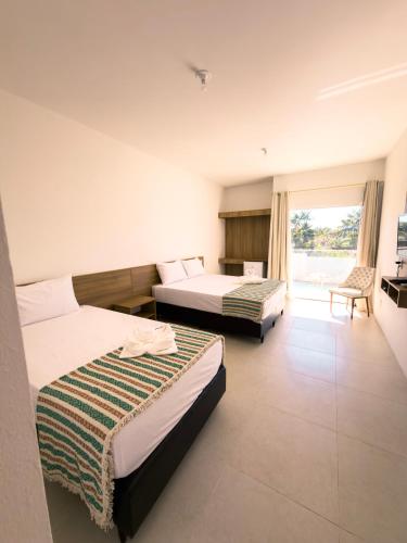 a hotel room with two beds and a window at Pousada Brisa dos Lençóis in Barreirinhas