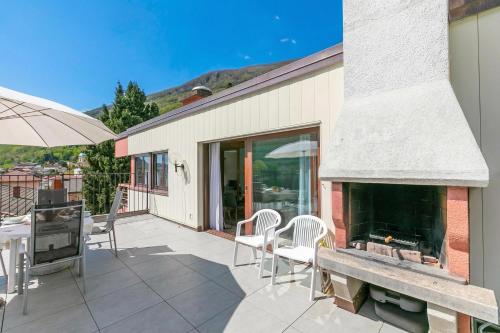 a patio with a fireplace and a table and chairs at Casa Bader - Lake View Apt with Pool & Sauna - Happy Rentals in Riva San Vitale