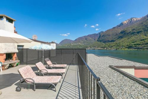 a patio with chairs and an umbrella next to a body of water at Casa Bader - Lake View Apt with Pool & Sauna - Happy Rentals in Riva San Vitale