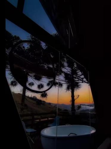 a bath tub in a room with a view of the sunset at Chalé Refúgio do Lobo in São Bento do Sapucaí
