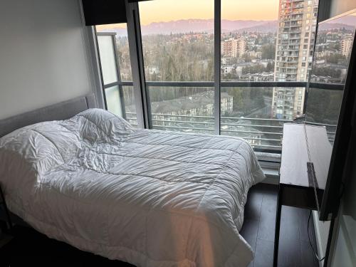 a bed in a room with a large window at Brentwood Retreat in Burnaby