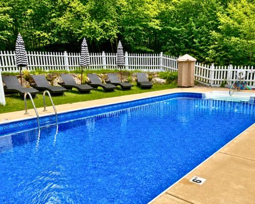 a swimming pool with chairs next to a white fence at The Aurora Inn & Cottages in Bartlett