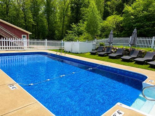 a swimming pool in a yard with chairs and a fence at The Aurora Inn & Cottages in Bartlett