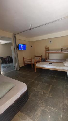 a room with two beds and a flat screen tv at Pousada Cantinho e Sossego casa 5 in Vespasiano