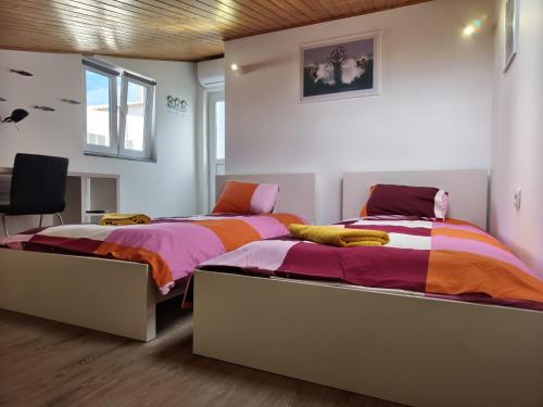 two twin beds in a room with white walls at North Wind House in Peniche
