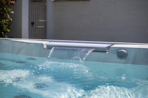 a pool of water pouring into a swimming pool at Villa Karina - Luxury Suite, Jacuzzi Pool & Garden Ostia Rome in Lido di Ostia