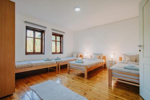 a room with two beds and a table and two windows at Kuća Mitića in Pirot