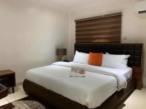 a bedroom with a large bed with an orange pillow at Trendy Inn limited in Lagos