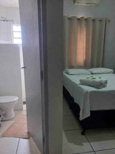 a bedroom with a bed and a bathroom with a toilet at Hotel Vale do Sol in Votuporanga