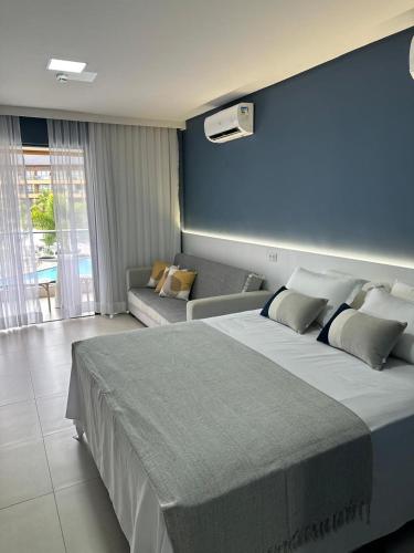 a bedroom with a large bed and a couch at Flat com vista linda Eco Resort in Tamandaré