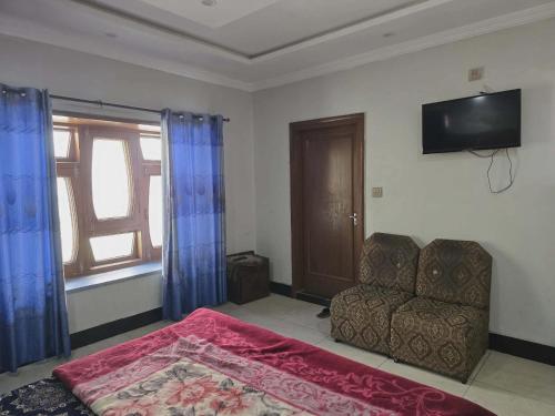 a bedroom with a couch and a television on the wall at Nice Guest House GPO Murree in Murree