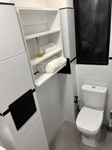 a white bathroom with a toilet and towels on shelves at Montevideo Centro in Montevideo