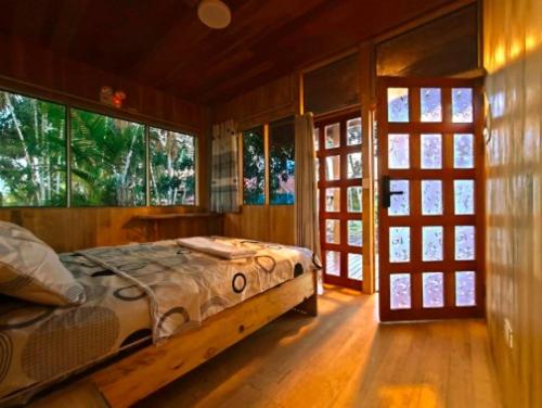 a bedroom with a bed in a room with windows at Retazos Eco Hotel in Iquitos