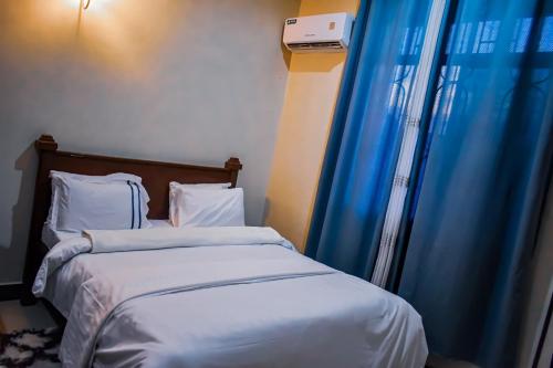ein Schlafzimmer mit zwei Betten mit blauen Vorhängen in der Unterkunft Jackpot Inn in Mbweni