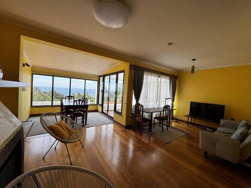 a living room with yellow walls and a table and chairs at Machico View in Machico