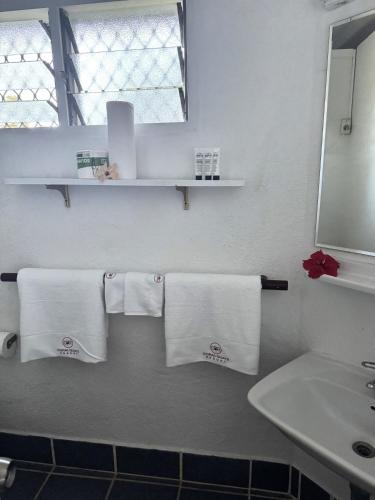 a bathroom with white towels and a sink and a mirror at Coral Quays Resort in Luganville