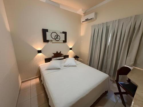 a bedroom with a white bed and a chair at Hotel Morada do Sol in Chavantina