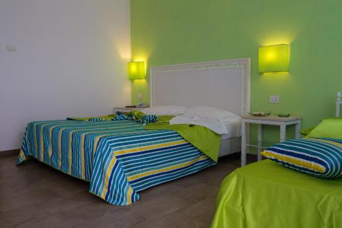 two beds in a room with green walls at Hotel O'scià in Lampedusa