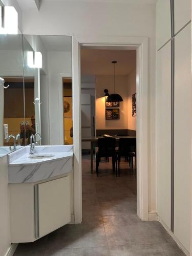 a bathroom with a sink and a dining room at Apto Riviera Piscina Aquecida in Bertioga